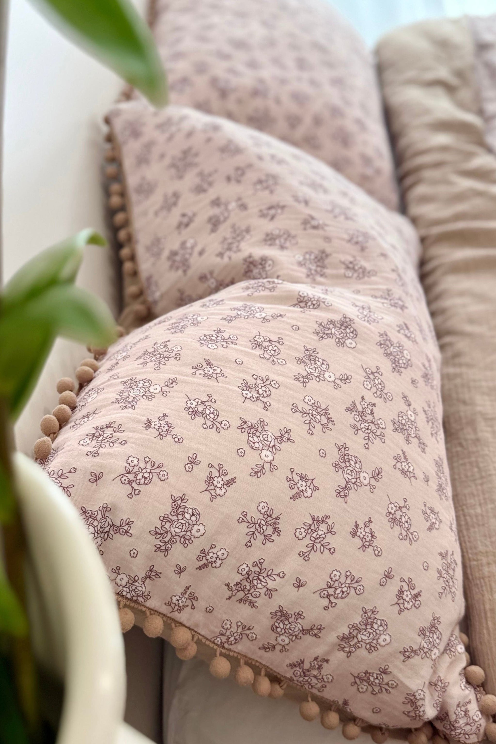 Floral-patterned cushion on a beige sofa with a blurred background