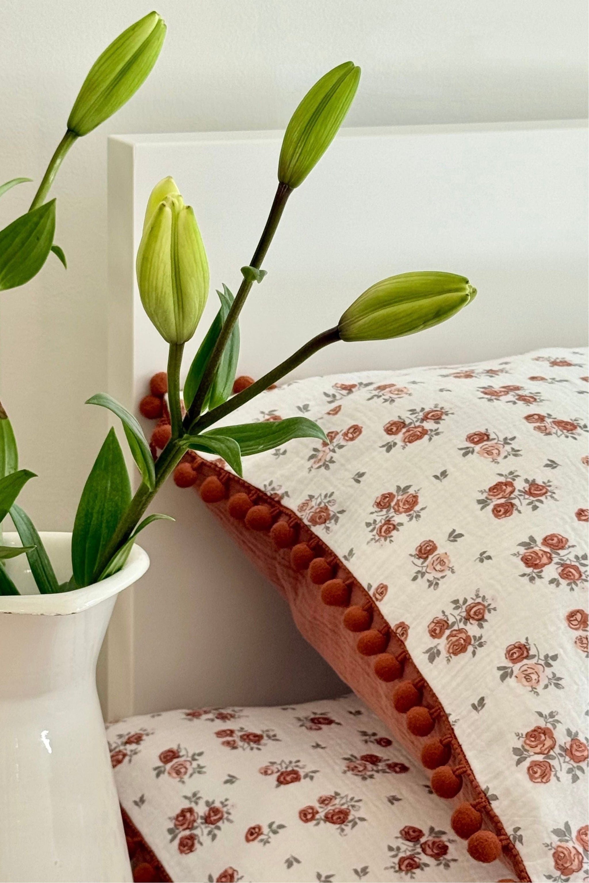Floral-patterned fabric with a white vase containing green leaves on a neutral background