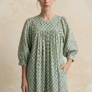 Woman wearing a green patterned dress against a beige background