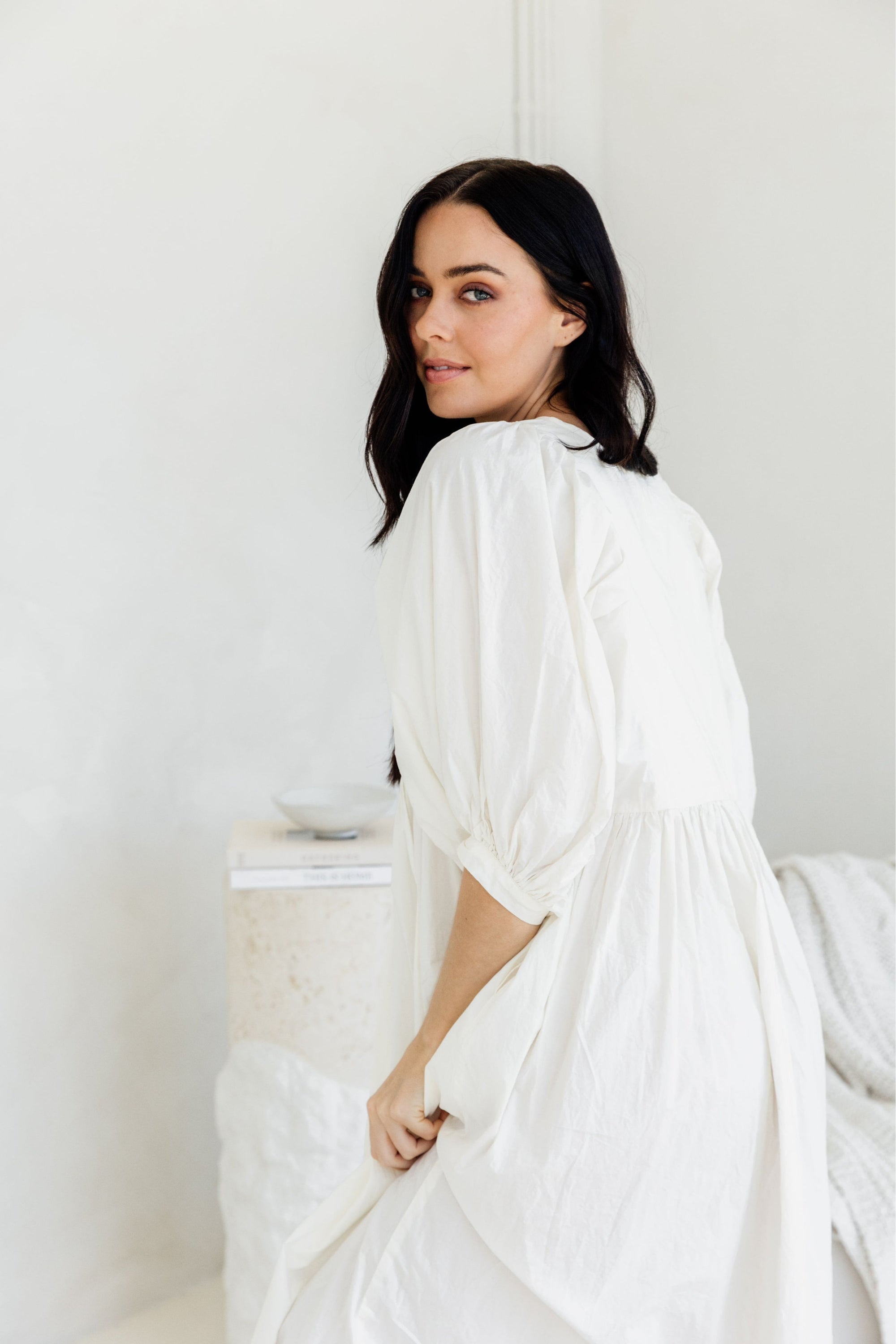 Woman wearing a white dress against a plain background