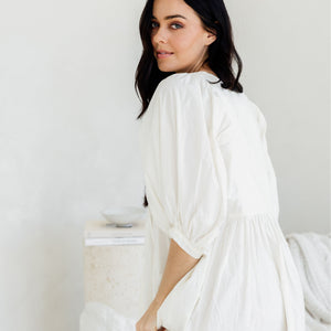 Woman wearing a white dress against a plain background